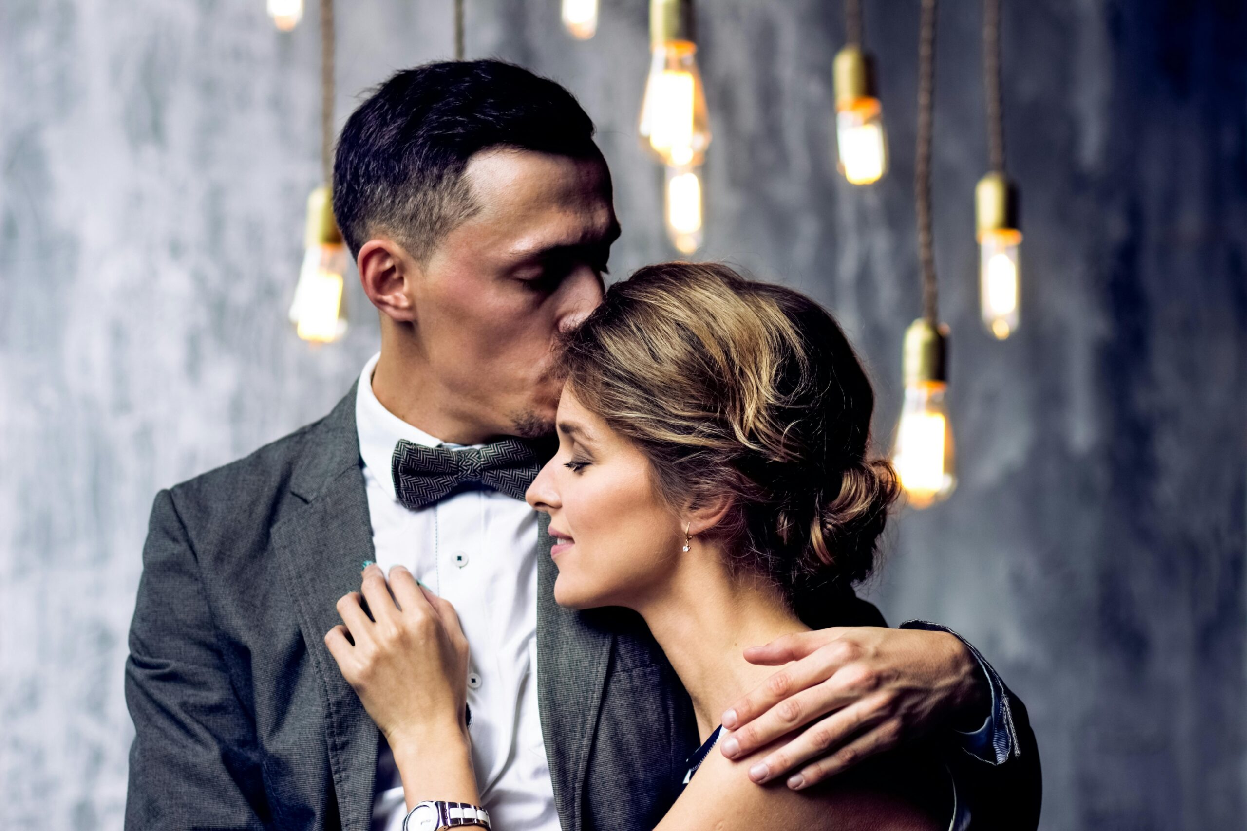 man kissing woman on forehead